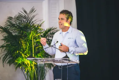 Andy Woolley speaking at the lectern at THRIVE 2025 in Nassau